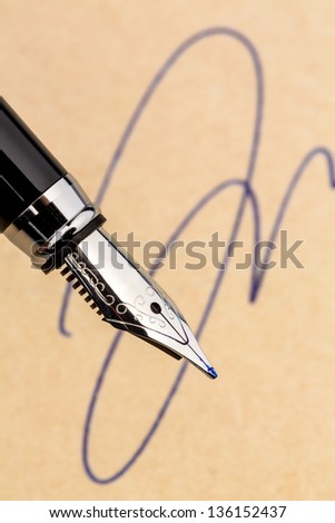 a fountain pen and a signature on yellow paper. symbolic photo for contract, and graphology testament