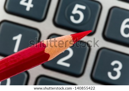 a red pen is on a calculator. save on costs, expenses and budget for bad economy