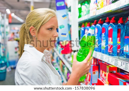 a young woman buys cleaning products for cleaning in a supermarket.