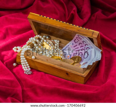 gold coins and bars with decorations on red velvet. symbolic photo for wealth, luxury, wealth tax.