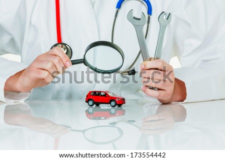 a model of a car is examined by a doctor. symbolic photo for workshop, service and car buying.