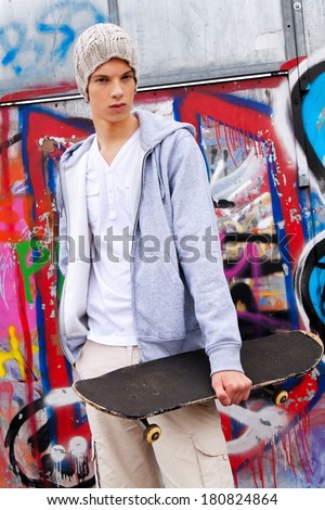 a cool-looking teenager man in front of graffiti