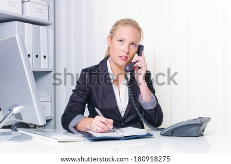 a friendly woman on the phone at her desk in the office and recorded dates on the calendar