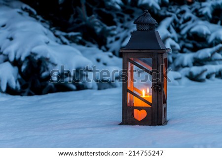 a lantern lights up in the snow at christmas. romantic light on one evening in the winter. peace and quiet