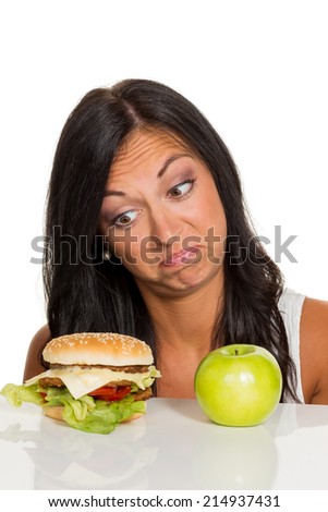 a young woman can not decide between a hamburger and an apple is. healthy or unhealthy diet.