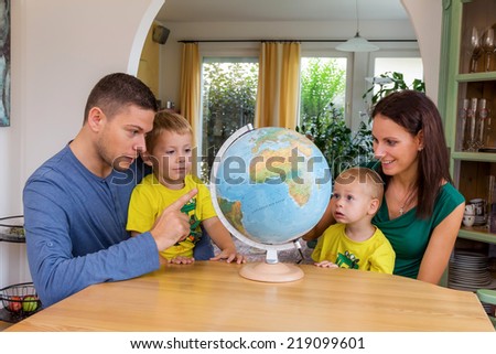 a family sitting at a globe and is planning a trip in the holidays
