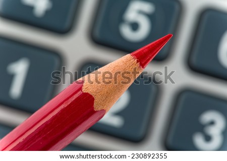 a red pen is on a calculator. save on costs, expenditures and budget for bad economy