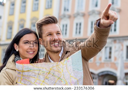 young couple with map and guide during a tour of town on vacation