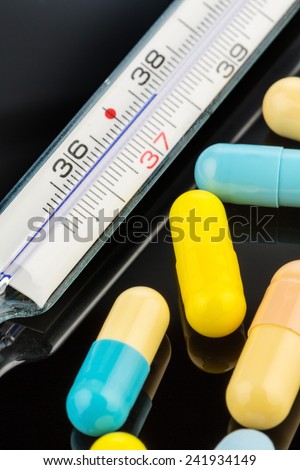 a clinical thermometer and tablets. symbolic photo for flu and colds