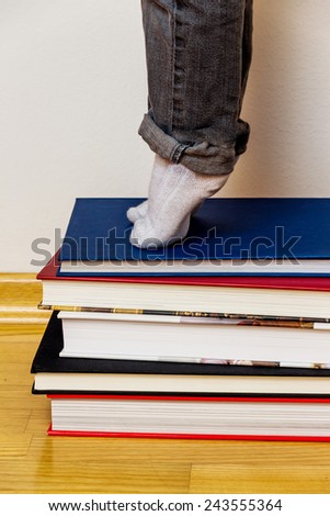 child standing on a pile of books, symbolizing education, reading, learning support