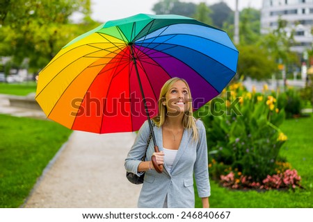 a young woman walks with a colorful umbrella in hand walking in the rain