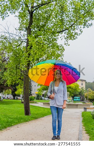 a young woman walks with a colorful umbrella in his hand walking in the rain.