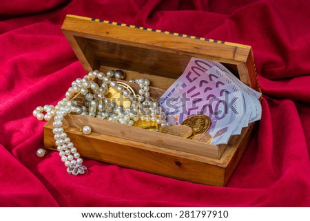 gold in coins and bars with decorations on red velvet. symbolic photo for wealth, luxury, wealth tax.