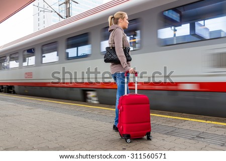 a young woman waiting for a train at a station. train holidays