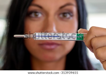 a woman holding a clinical thermometer hindquarters. symbolic photo for sick and fever