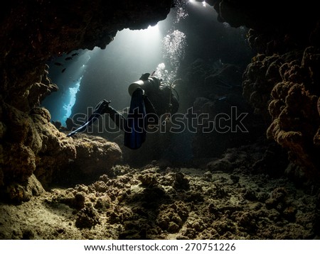 Diver passing through underwater cavern. Fury Shoal reefs, Southern Egypt.