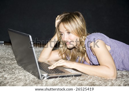 woman laying down and working on a laptop computer at home