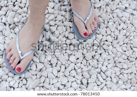 feet of a caucasian woman wearing red nail-polish and flip-flops