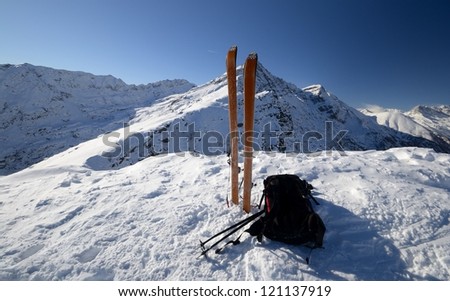 Pair of back country - tour ski and a backpack on the top of the mountain in a scenic high country background.
