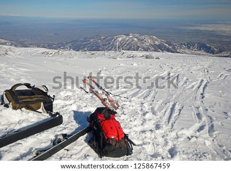 Back country skies and backpacks with avalanche safety tools in scenic winter mountain background