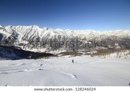 Ski alpinist on candid off-piste ski slope in powder snow and scenic alpine background