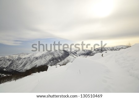 Back country ski tracks in scenic winter mountainscape and cloudscape in backlight effect