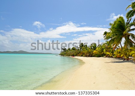 The gorgeous turquoise sea and desert beach in Ee Island. Woman walking on the beach. Location: Aitutaki atoll, Cook Islands.
