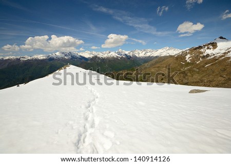 Snowcapped mountain ridge leading the view to the scenic high mountain peaks in the background. Location: italian Alps, Piedmont, Italy