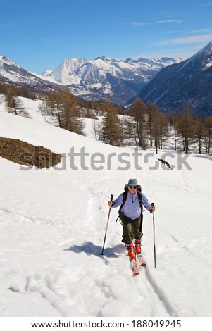 Tour skier hiking uphill under a bright sun in spring.