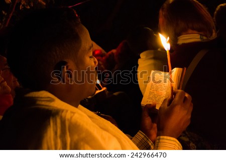 Gonder, Ethiopia - January 20, 2012: priest holding a candle in the night and reading a book in Geez, the old language of the church, during the Timkat, Ethiopian Orthodox celebration of Epiphany.