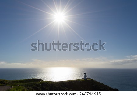 The lighthouse of Cape Reinga in the Far North, New Zealand. Shot in backlight with the sunstar. Natural landmark, where Tasman Sea meets Pacific Ocean.
