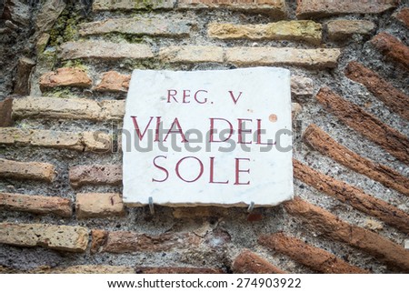 Ancient roman signpost in Ostia old town, Rome, Italy. Broken, weathered and damaged marble roman inscription, placed on brick boundary wall.