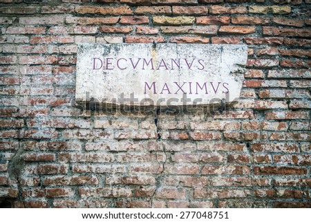 Decumanus Maximus (transl. Main Roman Road) sign in Ostia old town, Rome, Italy. Broken, weathered and damaged marble inscription, placed on brick wall. Dramatic vintage effect and vignetting added.