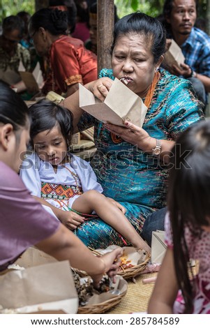 Sangalla, Indonesia - September 8, 2014: Children with mature woman of Toraja ethnicity in traditional attire having meal in Sangalla, Sulawesi, Indonesia.