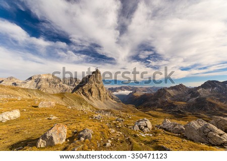Panoramic view of high mountain range in a colorful autumn with green yellow meadows and rocky mountain peaks. Wide angle shot in the Italian French Alps.