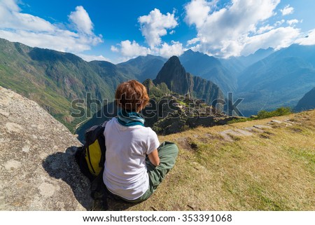 One person sitting in contemplation of Machu Picchu from the terrace above on daytime. The Inca\'s city is the most visited travel destination in Peru.