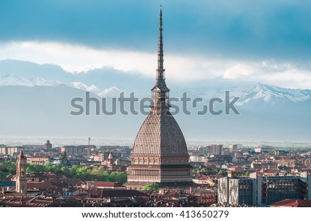 Cityscape of Torino (Turin, Italy) at sunset with details of the Mole Antonelliana towering on the city. Wind storm clouds over the Alps in the background.