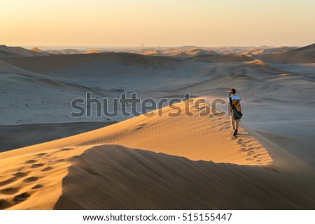 Tourist walking on the scenic dunes of Sossusvlei, Namib desert, Namib Naukluft National Park, Namibia. Afternoon light. Adventure and exploration in Africa.