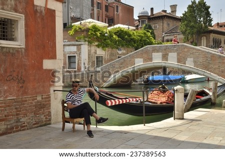 VENICE, ITALY - AUGUST 11: Gondolier sitting next to his gondola next to Marcello bridge on August 11, 2014 in Venice, Italy
