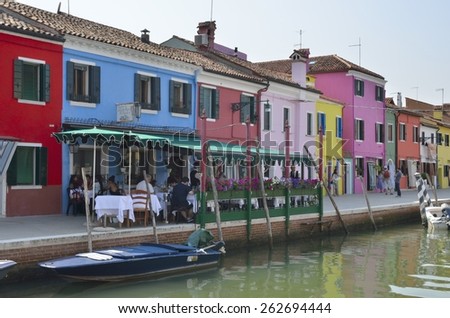 BURANO, ITALY - AUGUST 10: People having lunch in an outdoor restaurant next to the canal on August 10, 2014 in Burano, a fisher island of Venice, Italy
