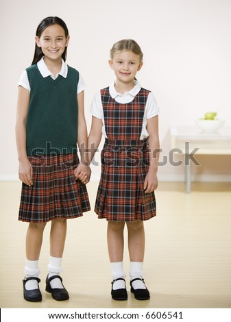 Two young girls holding hands in uniform.