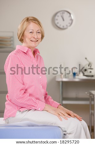 Senior woman sitting on exam table during medical checkup
