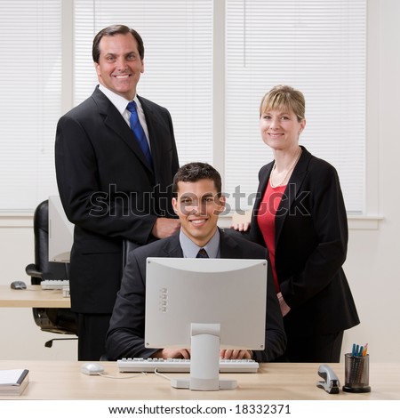 Happy, confident co-workers standing at desk