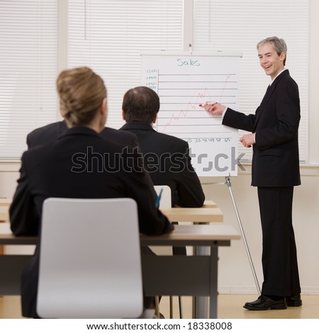 Businessman explaining presentation of financial line graph to co-workers