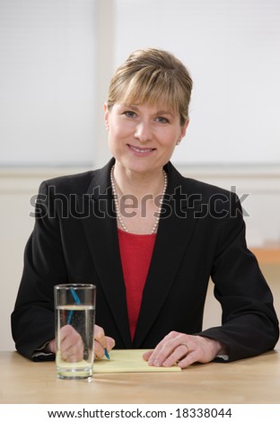 Smiling businesswoman writing on legal pad taking notes