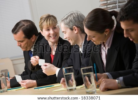 Co-workers exchanging business cards while sitting on panel