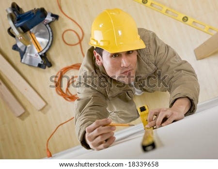 Construction worker in hard-hat using measuring tape for project