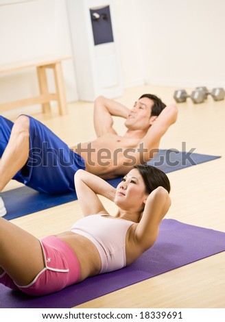 Determined man and woman doing stomach crunches in health club