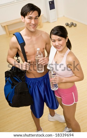 Fatigued man and woman holding water bottles in health club