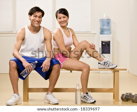 Fatigued man and woman holding water bottles in health club